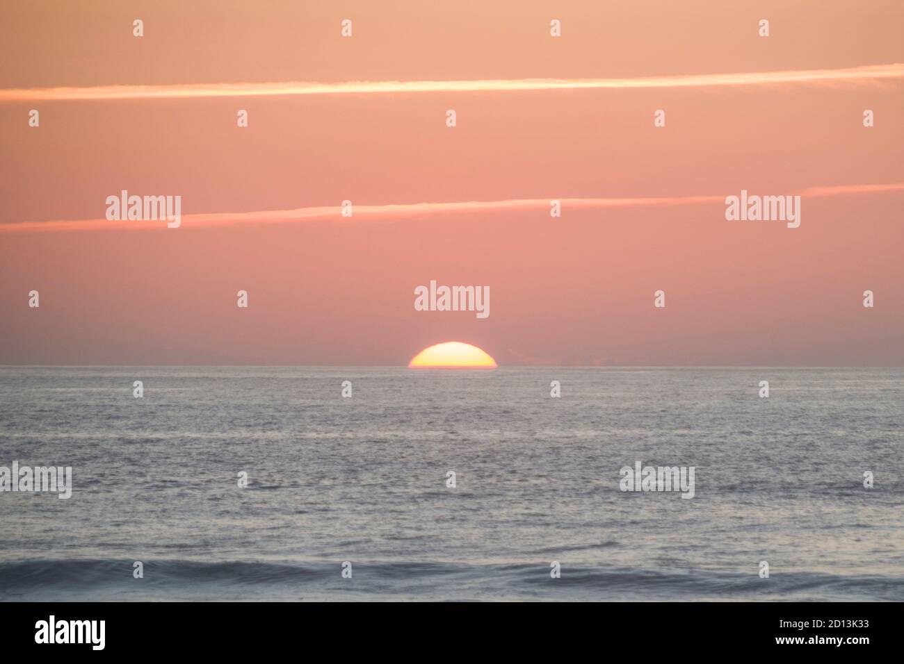 Grand soleil se coucher sur l'océan, presque disparaître la ligne d'horizon, avec un ton orange chaud et fort Banque D'Images