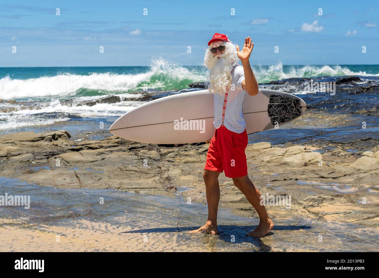 Le Père Noël avec une planche à voile avec l'océan sur le fond. Australie, Noël en été. Banque D'Images