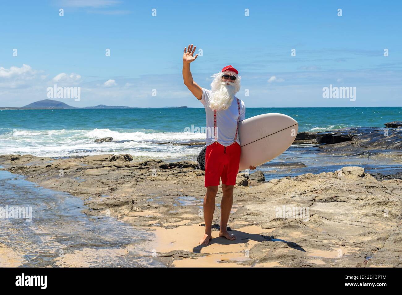 Le Père Noël avec une planche à voile avec l'océan sur le fond. Australie, Noël en été. Banque D'Images