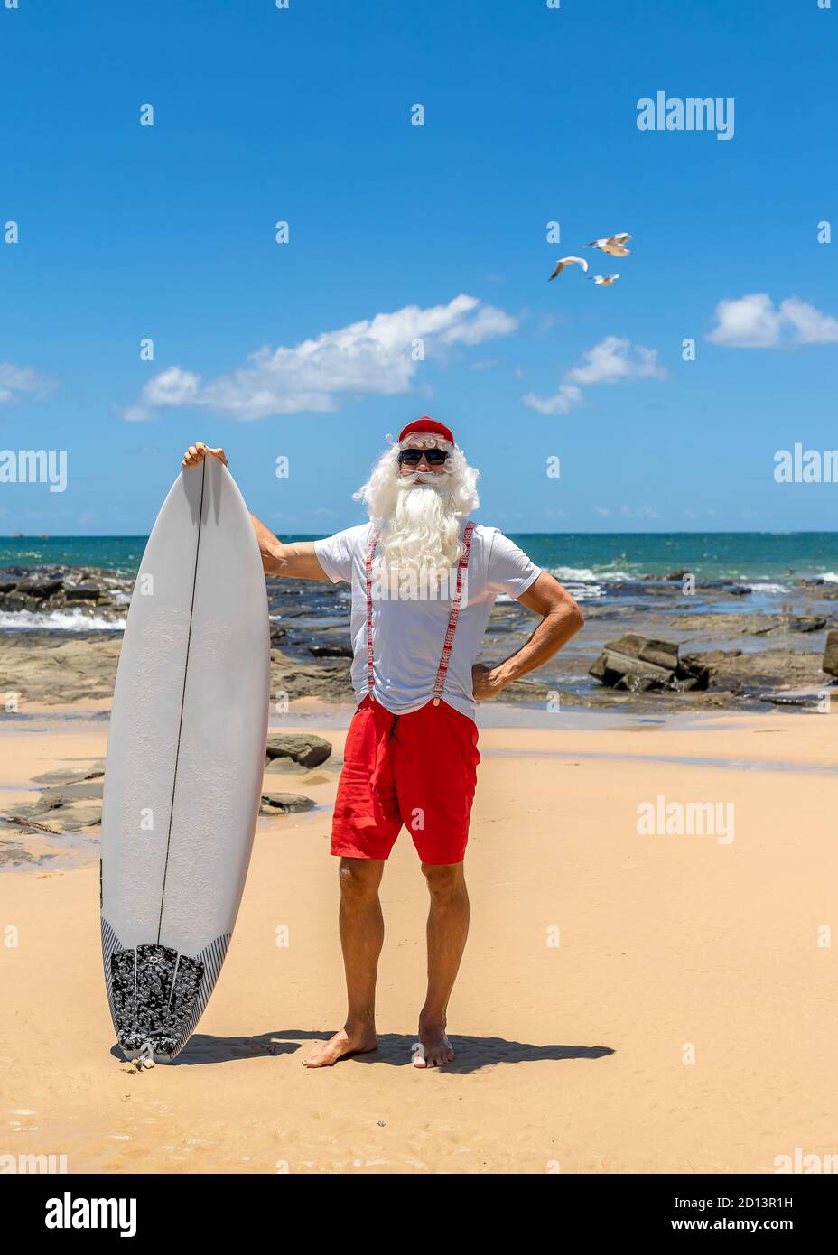 Le Père Noël avec une planche à voile avec l'océan sur le fond. Australie, Noël en été. Banque D'Images