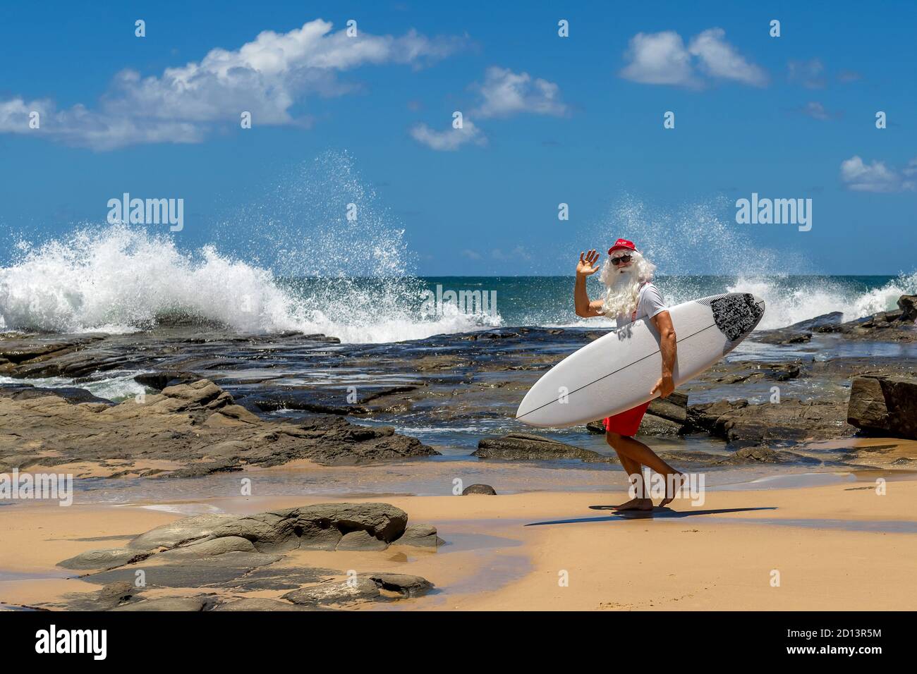 Le Père Noël avec une planche à voile avec l'océan sur le fond. Australie, Noël en été. Banque D'Images