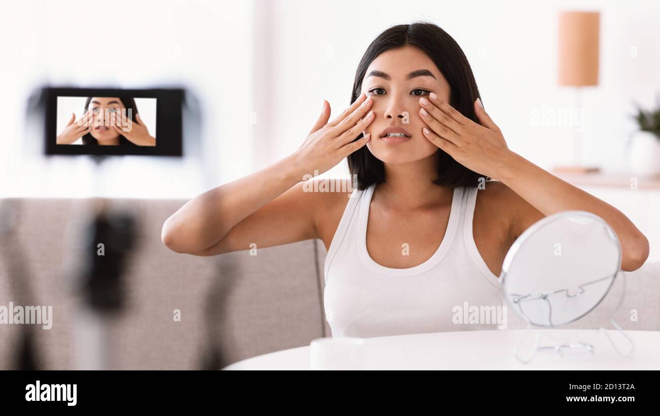 Jeune femme massant son visage pour vlog Banque D'Images