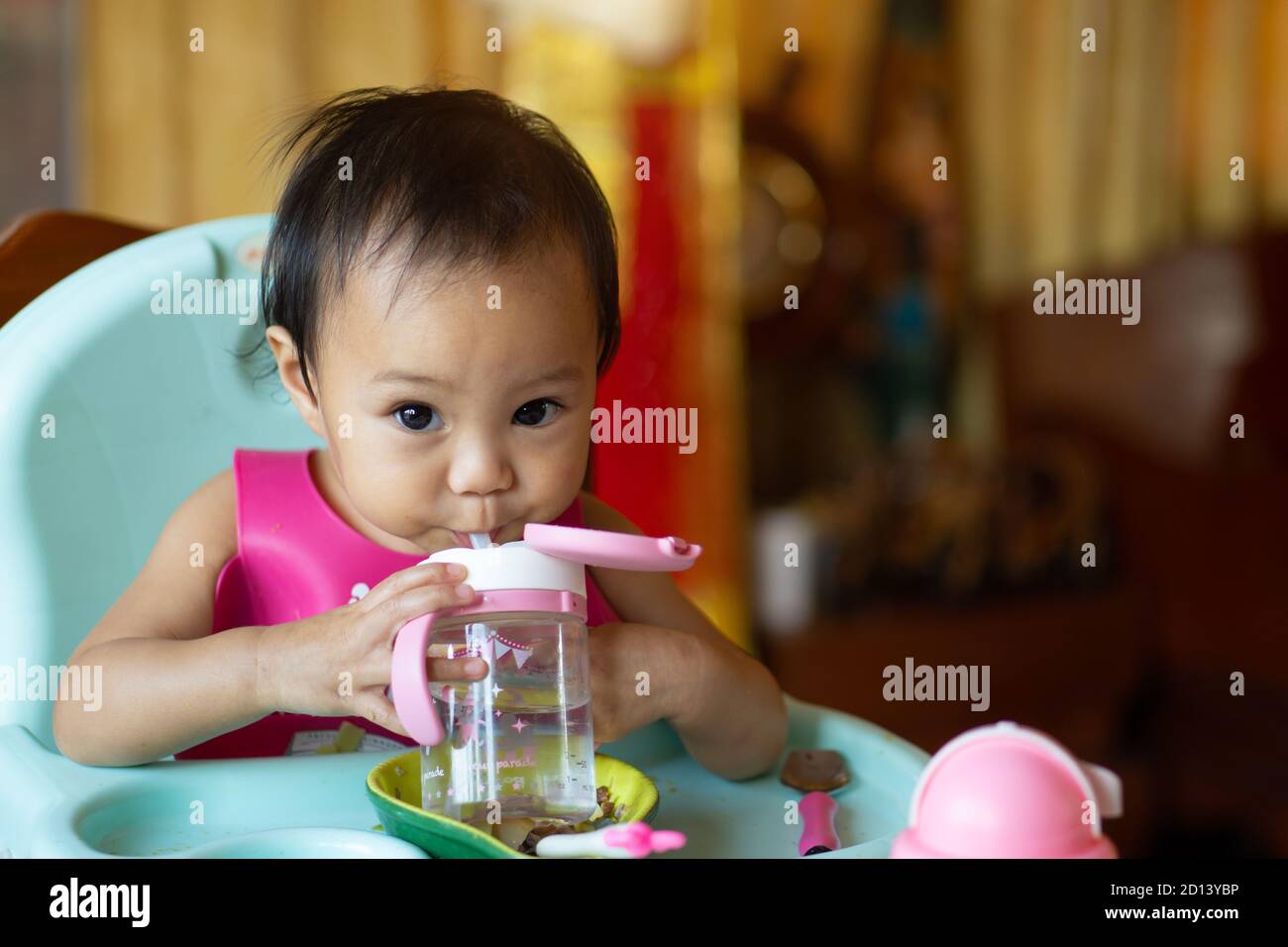 Fille asiatique 11 mois l'année est l'eau potable de bébé sur la nourriture de table de bébé. Banque D'Images