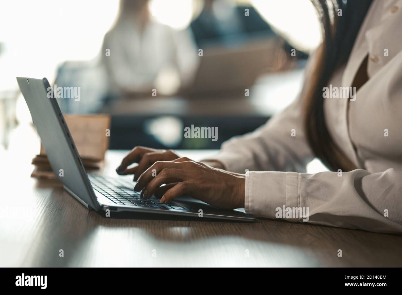 Office Manager saisissant le clavier de l'ordinateur portable. Collègues travaillant au bureau sur un arrière-plan flou. Image en tons. Gros plan sur les mains des femmes. Haute qualité Banque D'Images