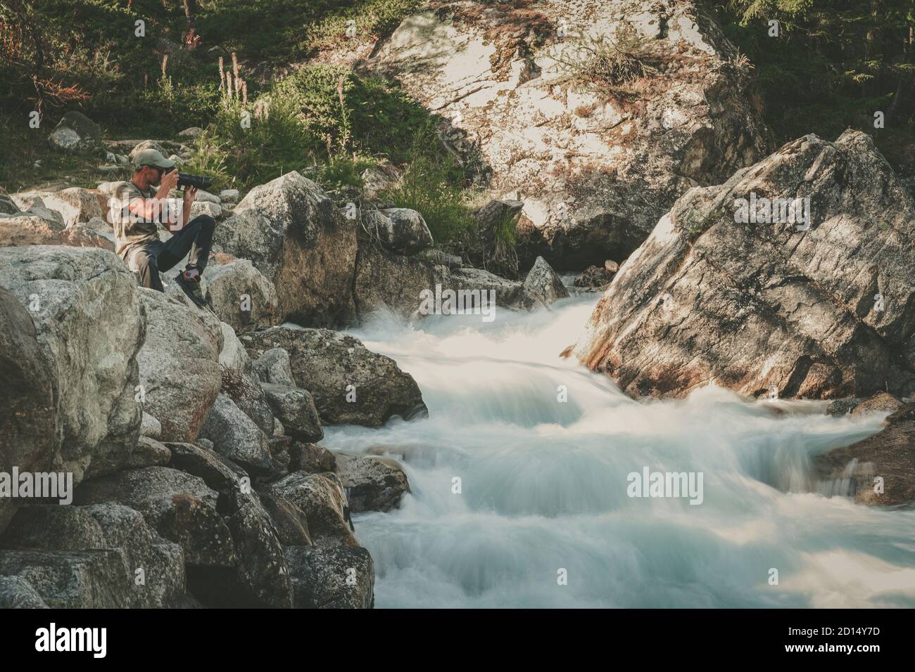 Photographe de paysage professionnel dans ses années 40 prendre des photos de la pittoresque cascade alpine. Thème de l'industrie de la photographie de voyage et de paysage. Banque D'Images