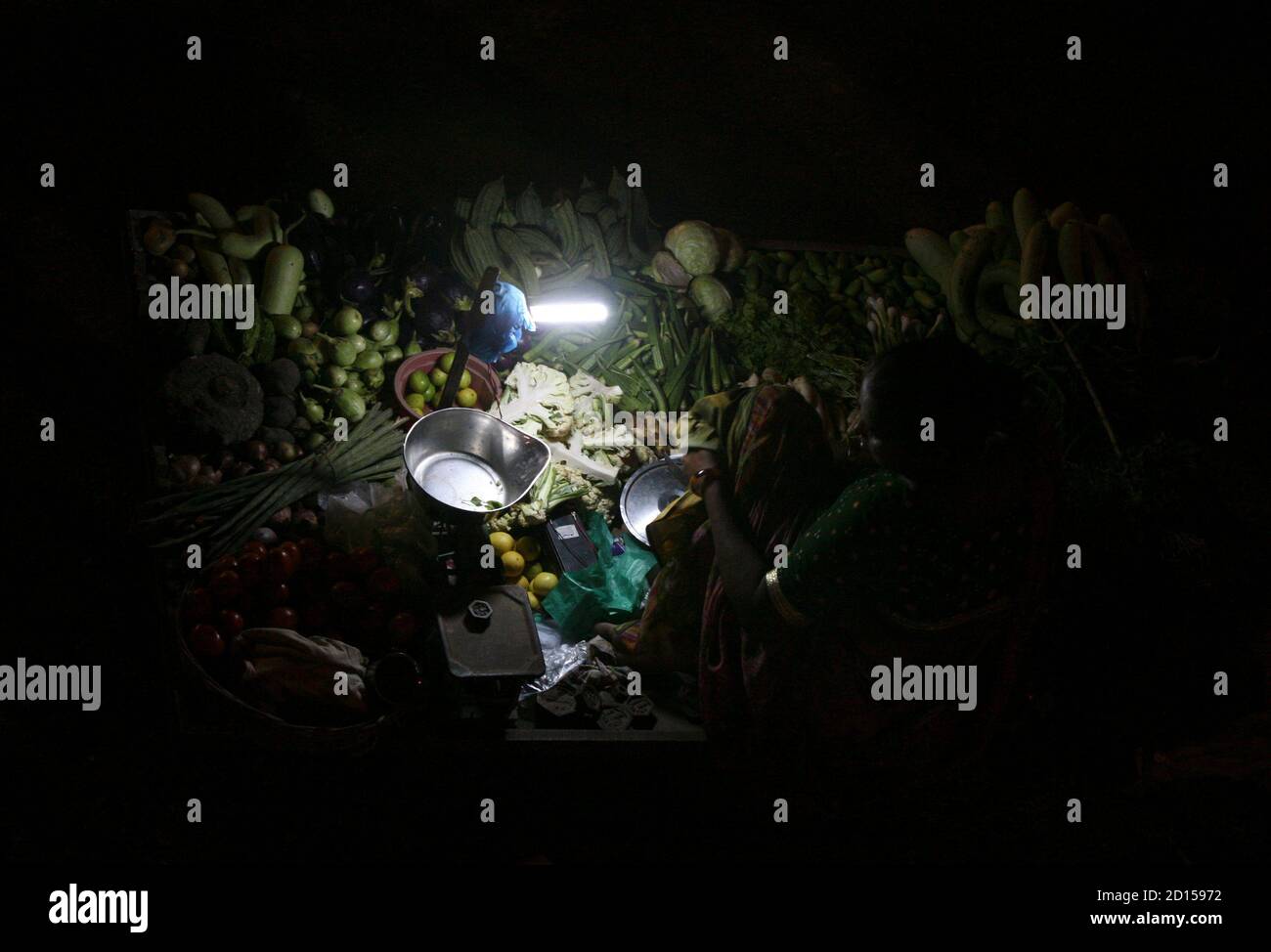 A vendor uses a solar powered light as she waits for customers at an open  air evening vegetable and fruit market in the western Indian city of  Ahmedabad September 10, 2009. When