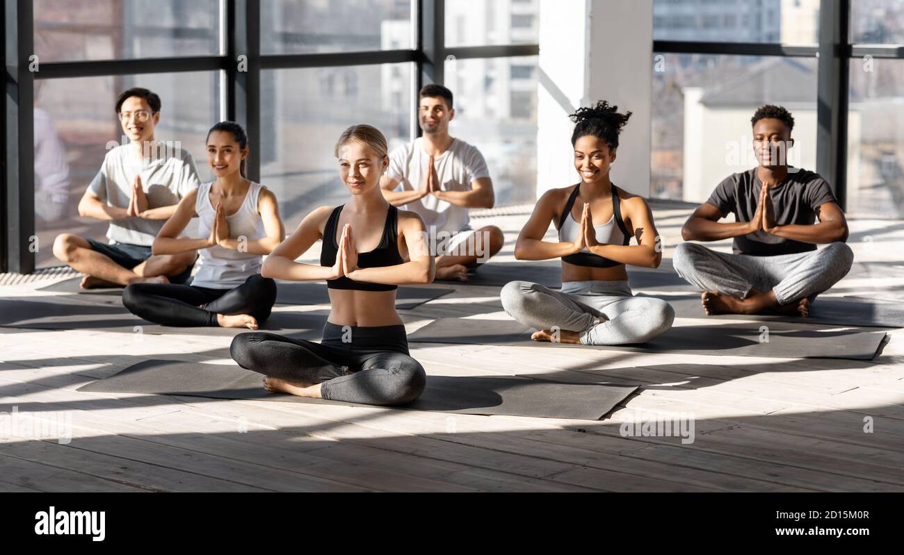 Formation de groupe. Des sportifs multiethniques méditant ensemble dans un studio moderne, pratiquant le yoga Banque D'Images