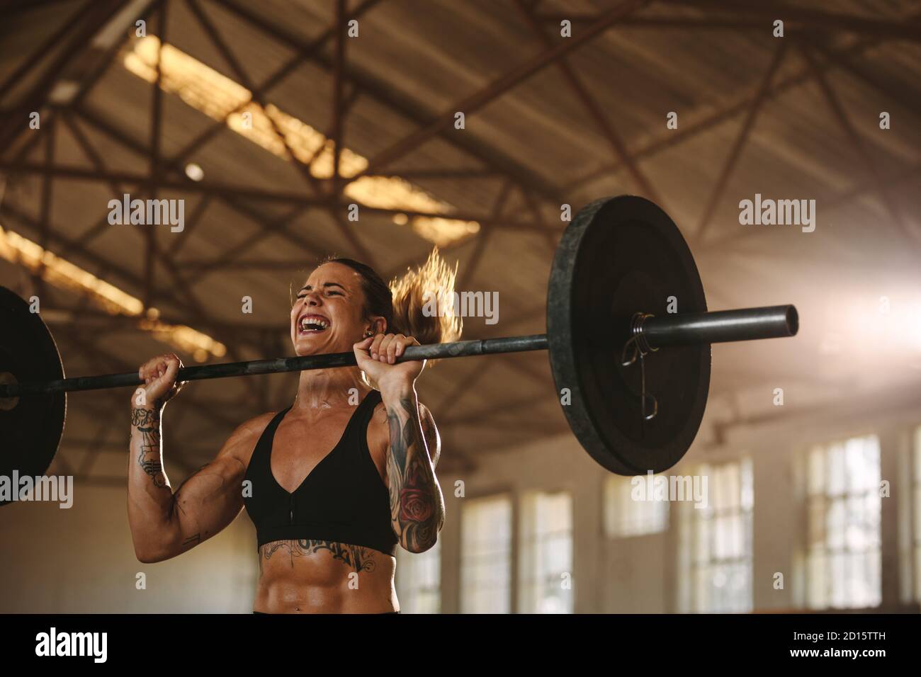 Une jeune femme robuste s'exerçant avec une barbell. Déterminez si une athlète féminine a des poids lourds. Banque D'Images