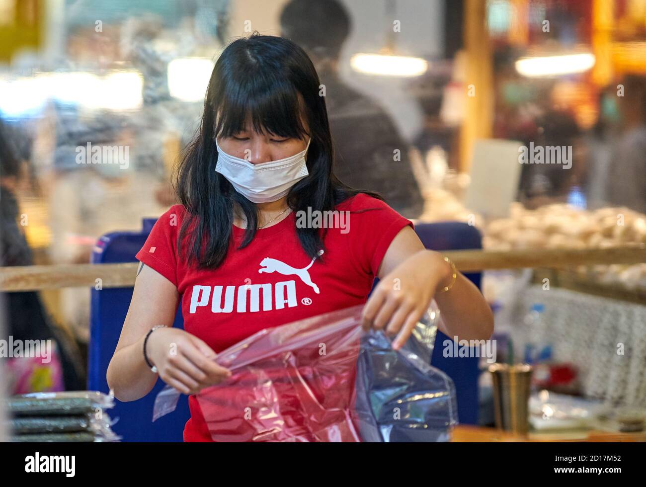 Une femme de vente dans un centre commercial portant un masque de protection. Banque D'Images