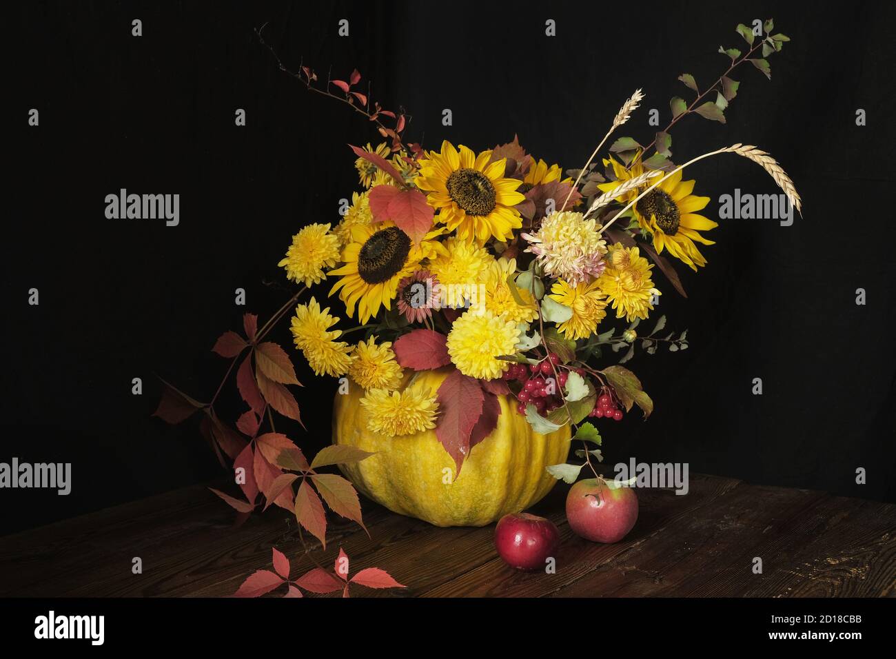 Arrangement de fleurs avec des tournesols dans une citrouille sur une table en bois sur un fond noir. Thanksgiving et concept d'espace de copie Banque D'Images