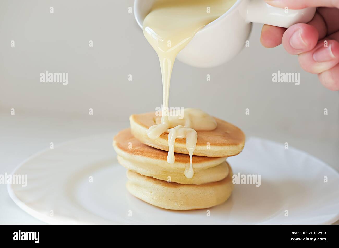 Petit Dejeuner Asiatique Tendance Crepes Japonaises Aux Souffles Sause A La Main Tenant Le Bateau A Vapeur Qui Verse La Creme Sur Trois Gateaux Chauds Sur Une Assiette Photo Stock Alamy