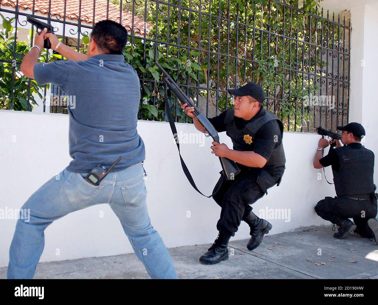 Les policiers ont visé leurs armes lorsqu'ils vérifient une maison après  une fusillade entre deux gangs à Cancun, dans l'est du Mexique, le 12  janvier 2008. Un homme armé soupçonné a été