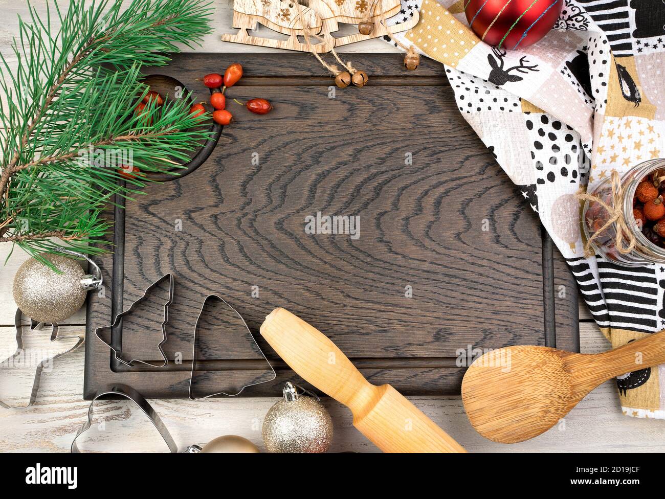 Planche à découper, rollpin, branche de pin et baies rouges sur fond de bois clair. Banque D'Images