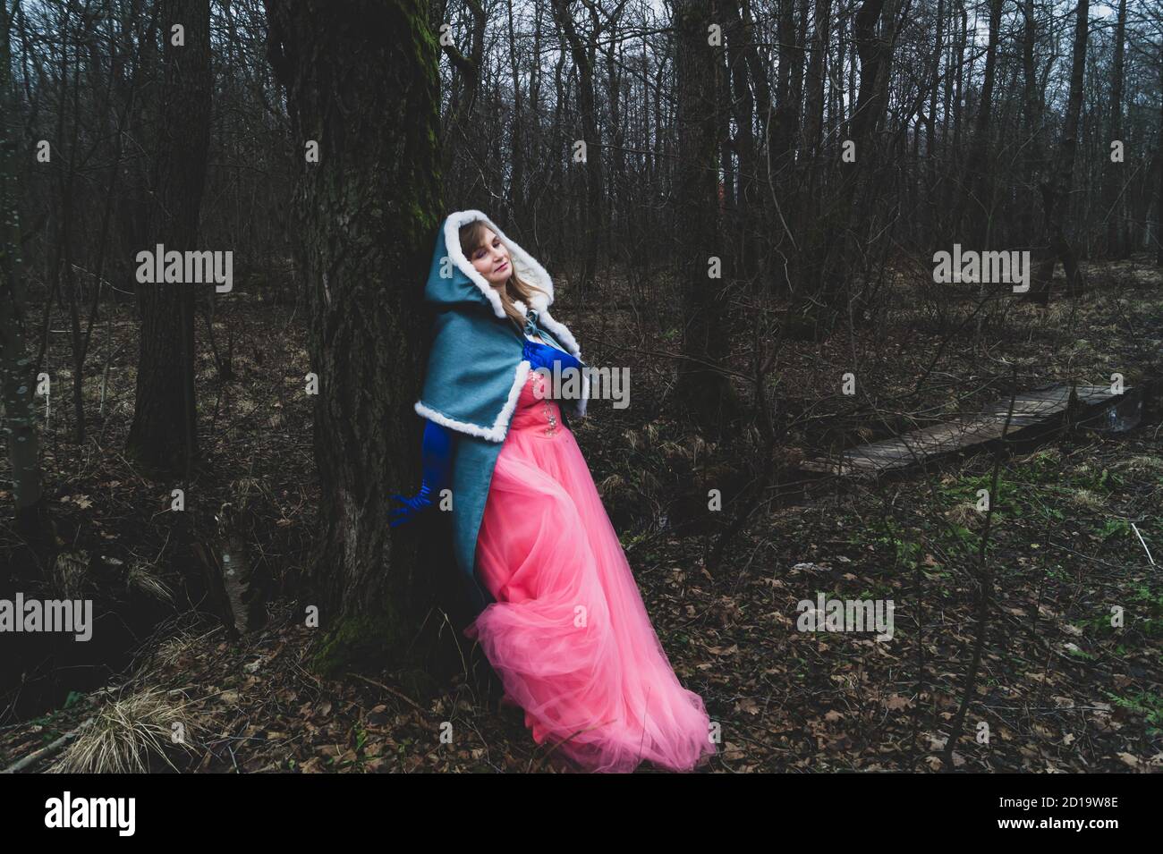 Femme avec manteau adossé contre un arbre. Femme adulte en costume  fantaisie avec cape. automne magique Photo Stock - Alamy