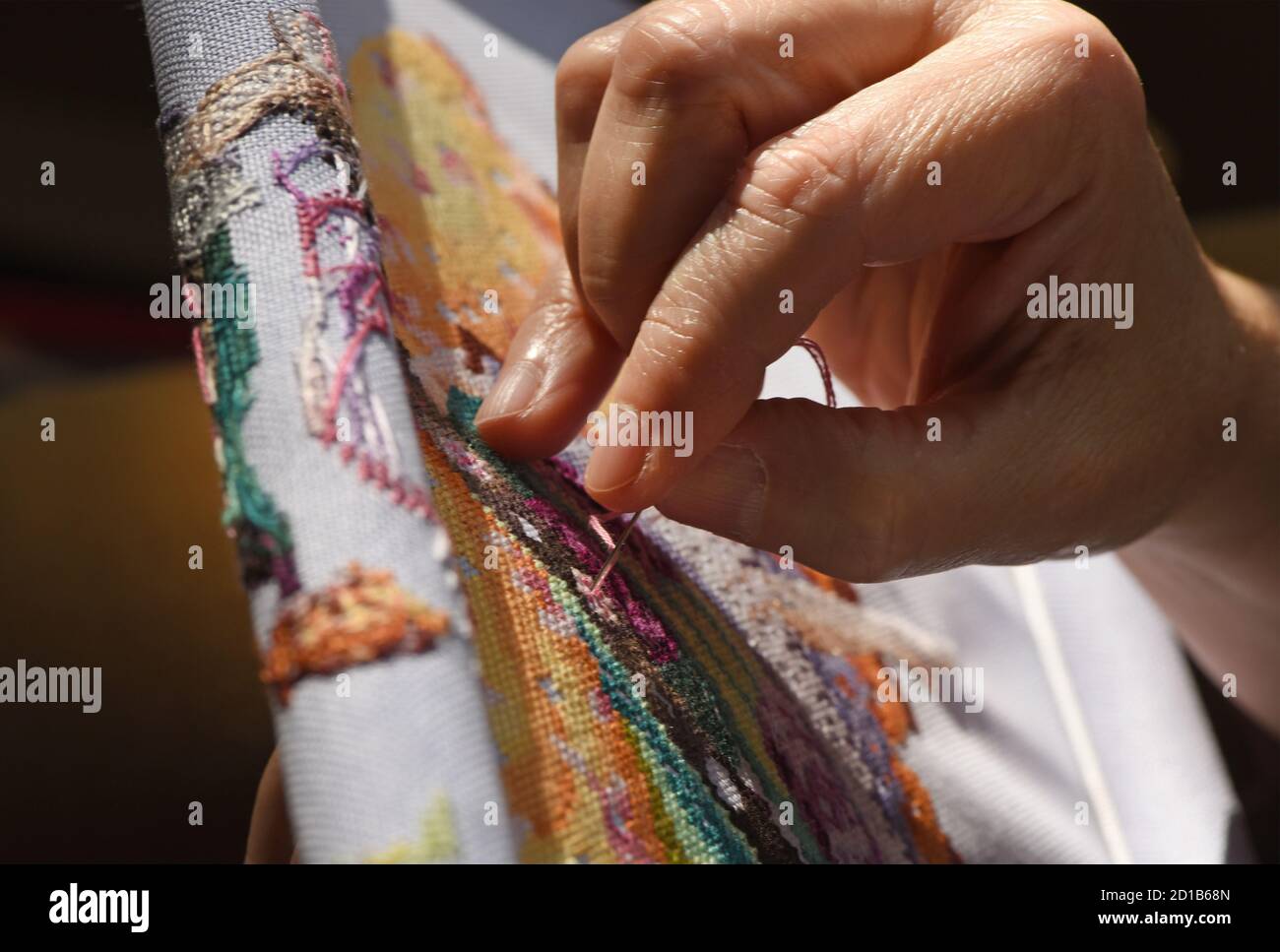 Une femme traverse un motif de point de croix de Miribilia sur un tissu à tissage de evenwey Banque D'Images