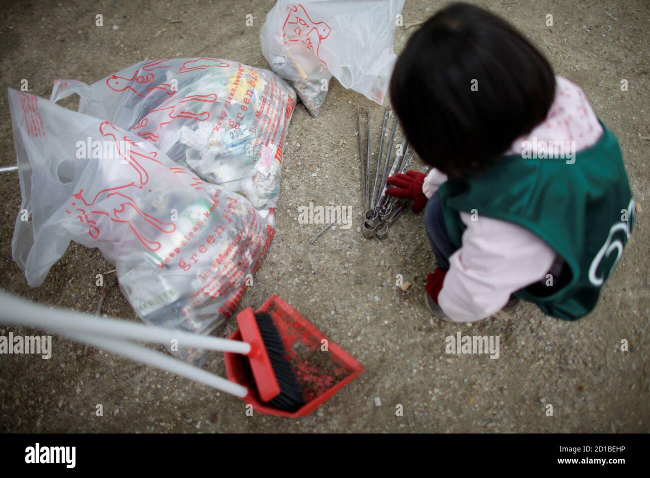 A Japanese child volunteer plays with tongs used to clear litter from  Avenue Champs Elysees in Paris April 19, 2009. A group of Japanese  expatriates staged a clean-up action at the famous