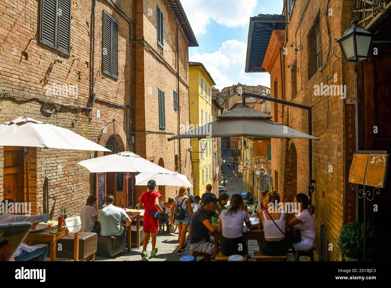 Touristes dans les restaurants de plein air de Costa Sant'Antonio, une ruelle étroite dans le centre historique de Sienne, UNESCO W.H. Site, en été, Toscane, Italie Banque D'Images