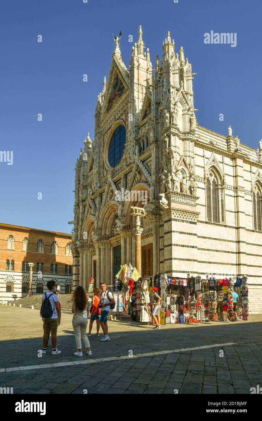 Vue extérieure de la cathédrale de Sienne (13ème siècle) de style roman-gothique, site classé au patrimoine mondial de l'UNESCO, avec stands de souvenirs et touristes, Toscane, Italie Banque D'Images