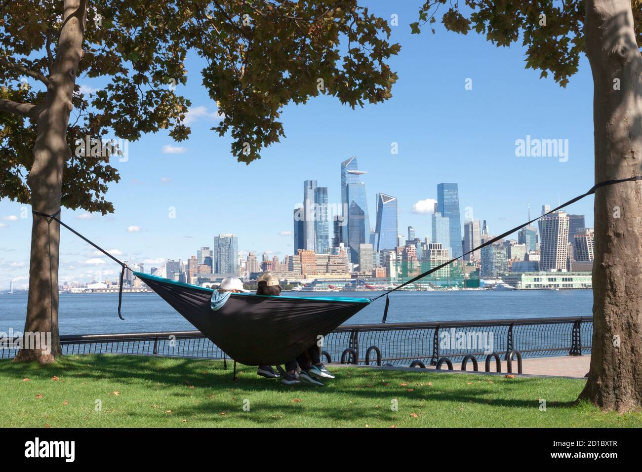 Couple dans hamac en profitant de la vue sur la ville de New York/Manhattan depuis l'autre côté de l'Hudson River à Hoboken, le bord de mer du New Jersey. Banque D'Images