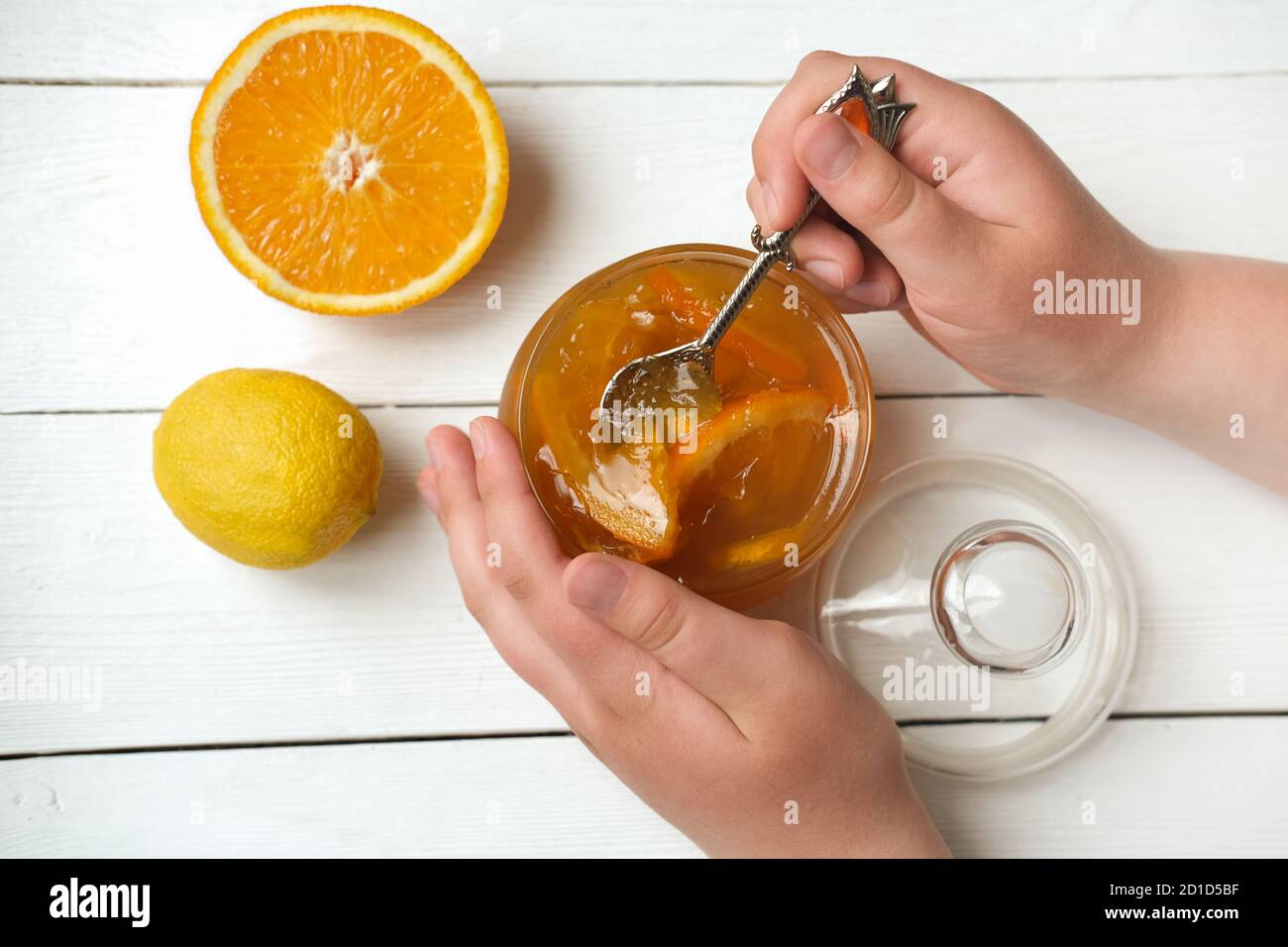 les mains de l'adolescent tiennent une cuillère avec de la confiture d'orange et de citron. marmelade d'orange maison. petit déjeuner dans un style rustique. récolte et préparation de gelée à l'automne. vue du dessus. préparation de confiture. Banque D'Images