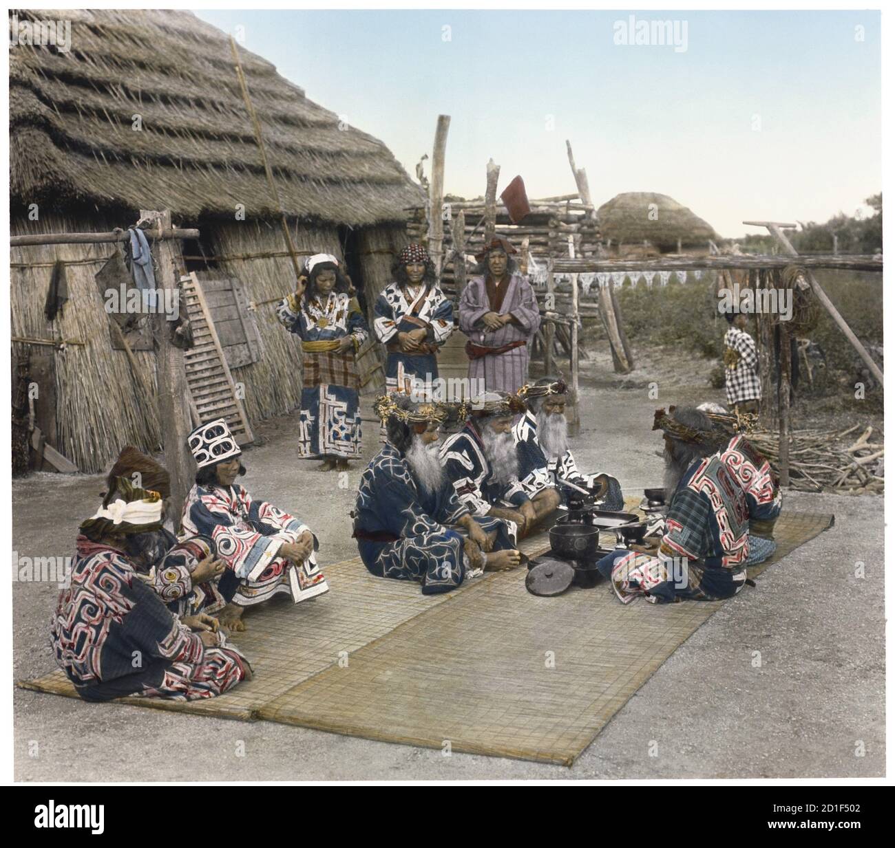Photo colorisée du peuple Ainu en robe traditionnelle préparant un festin, île Hokkaido, Japon, 1892. (Photo de Burton Holmes) Banque D'Images