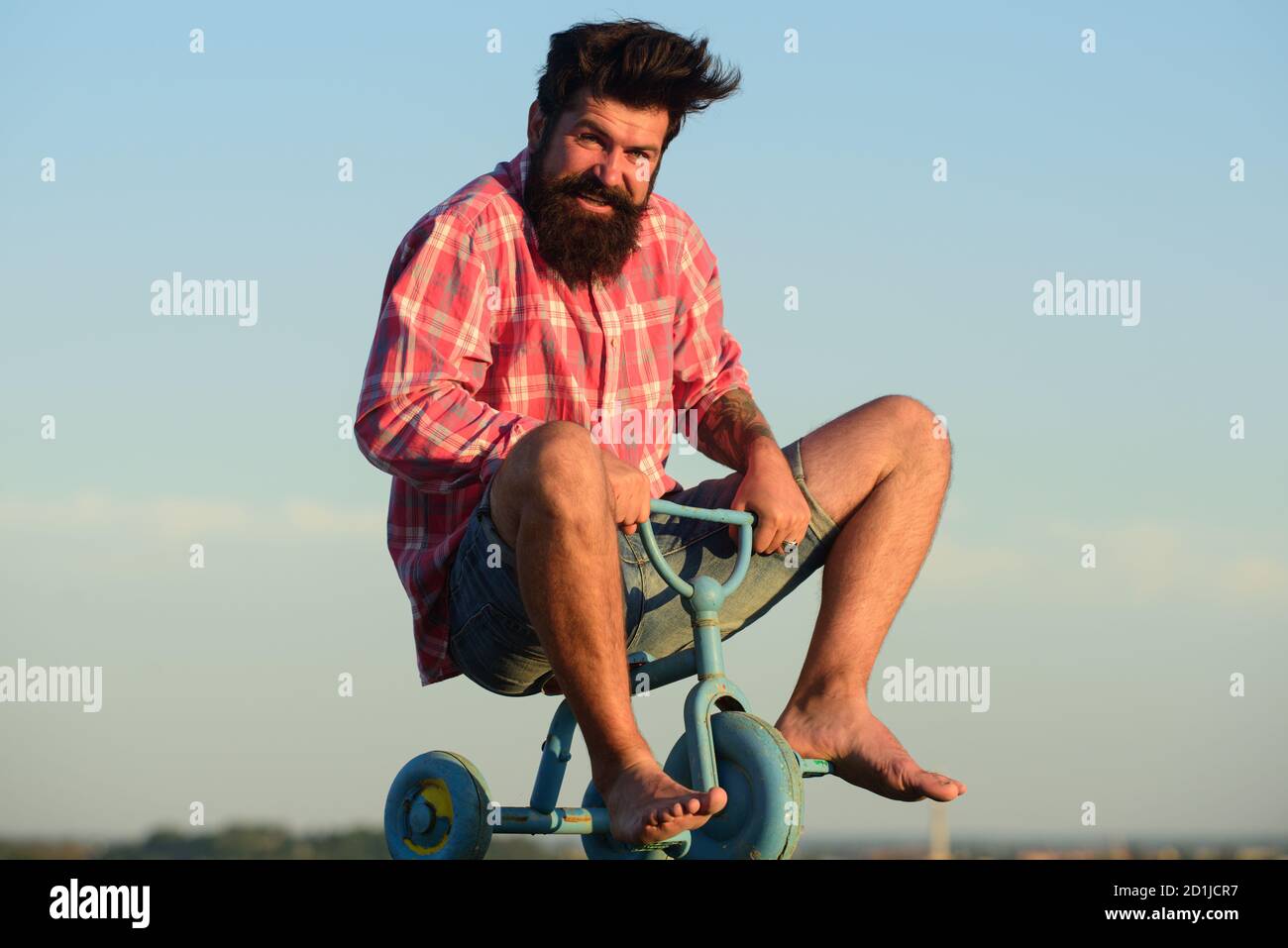 Homme agissant comme un enfant. Drôle d'homme sur un vélo pour enfants. Vélo nerdy. Banque D'Images