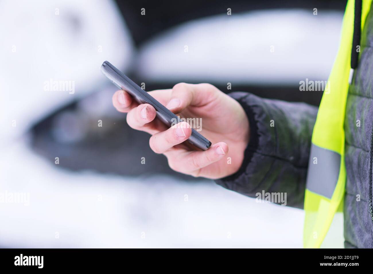 Vue rapprochée. Homme tenant le téléphone mobile et appelant les services de voiture d'hiver pour aider. Banque D'Images