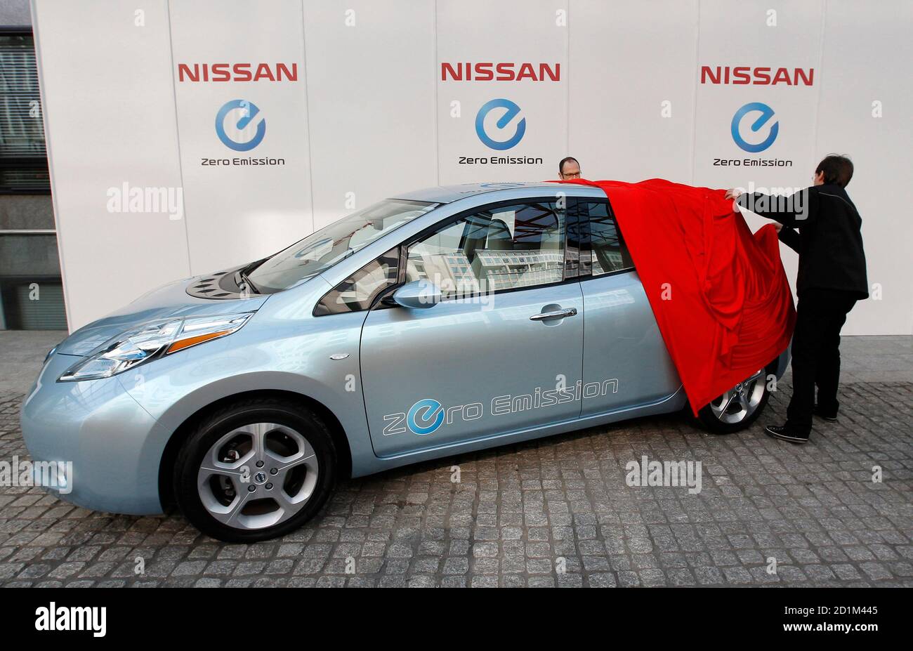Workers unveil a Nissan Leaf car outside the Department
