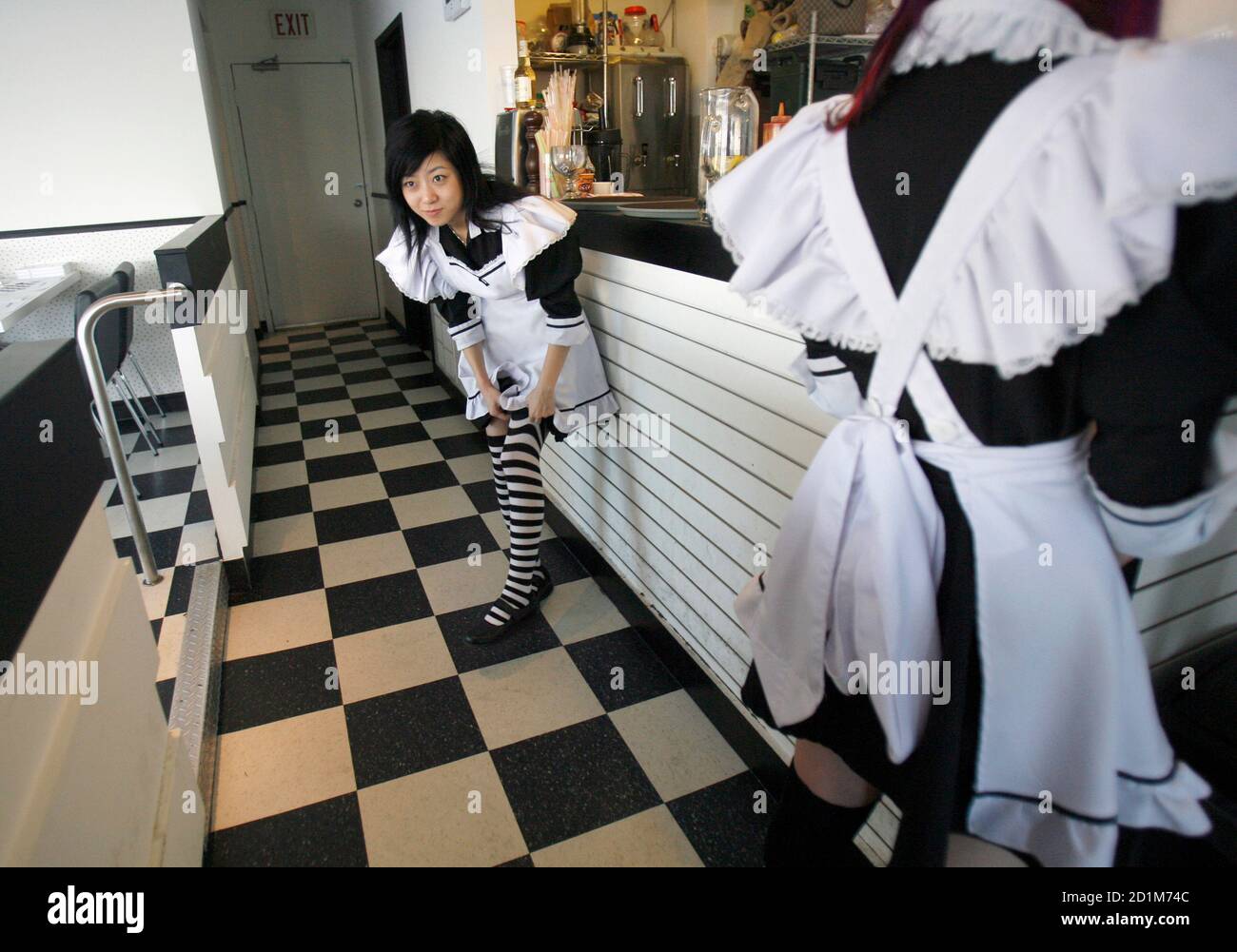 Cindy Wang (L) tire ses bas de cuisse, qui font partie de son uniforme de  serveuse française, tout en travaillant au café iMaid à Scarborough, le 5  décembre 2006. Le petit restaurant,