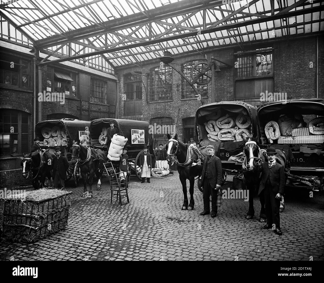 HEAL AND SON LIMITED, 195-199 Tottenham court Road, Londres. Le personnel et les chariots tirés par des chevaux chargés de matelas et de literie faits sur le site, posant dans la cour. Commandée par Heal and son Ltd, cette photographie a été prise par Bedford Lemere and Co. En mars 1897. Banque D'Images
