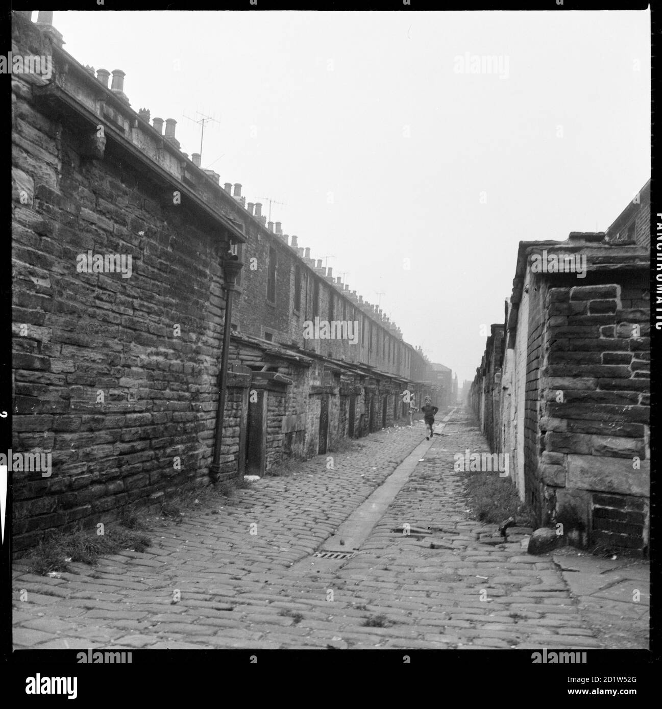 Une vue depuis Higgin Street en regardant le long de la canin pavée (ruelle arrière) entre Anne Street et Helena Street, Burnley, Lancashire, Royaume-Uni. Banque D'Images