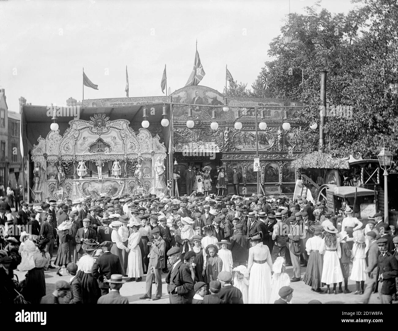 St Giles Fair avec son Royal Electric Coliseum décoré avec goût et un chariot de poisson frit et de pommes de terre à puce se trouve à côté de la lampe à gaz. Banque D'Images