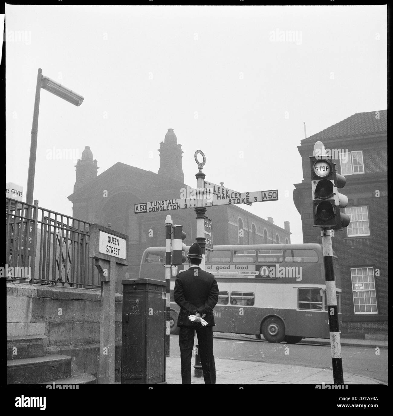Un policier debout à côté d'un panneau à la jonction de la rue Queen et de la place Swan avec l'église méthodiste centrale en arrière-plan. Banque D'Images