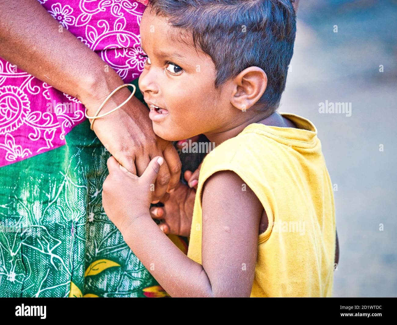 Pondichéry, Inde - décembre 2018, Circa. Embarassed timide non identifiés fils se tenant très près de sa mère à la rue d'un village dalit Banque D'Images