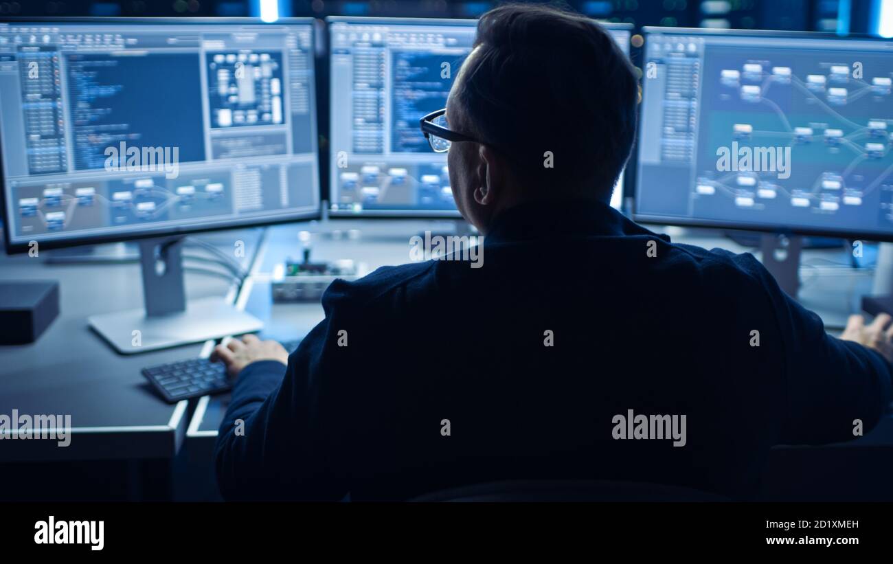 Programme informatique professionnel travaillant dans un centre de données sur un ordinateur de bureau avec trois écrans, faisant le développement de logiciels et de matériel. Affiche Afficher Banque D'Images