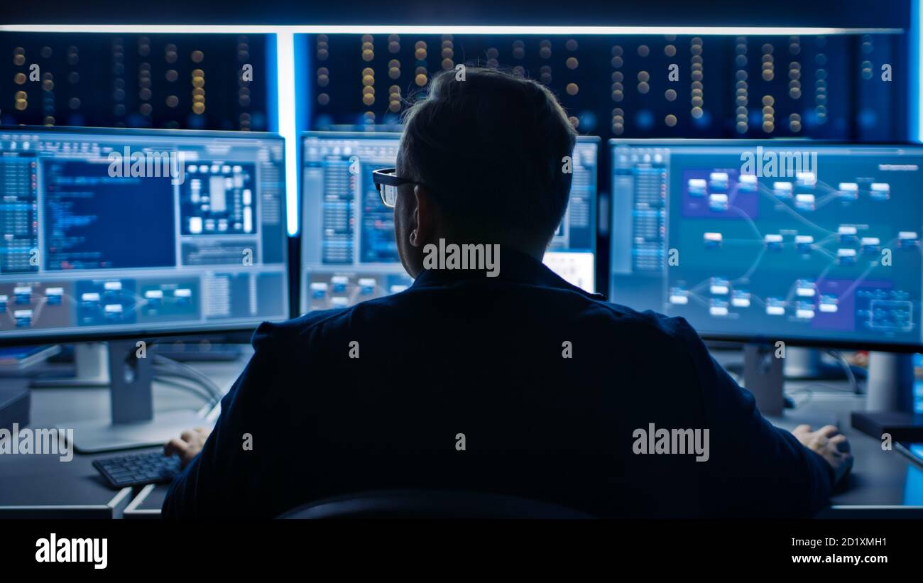 Programme informatique professionnel travaillant dans un centre de données sur un ordinateur de bureau avec trois écrans, faisant le développement de logiciels et de matériel. Affiche Afficher Banque D'Images