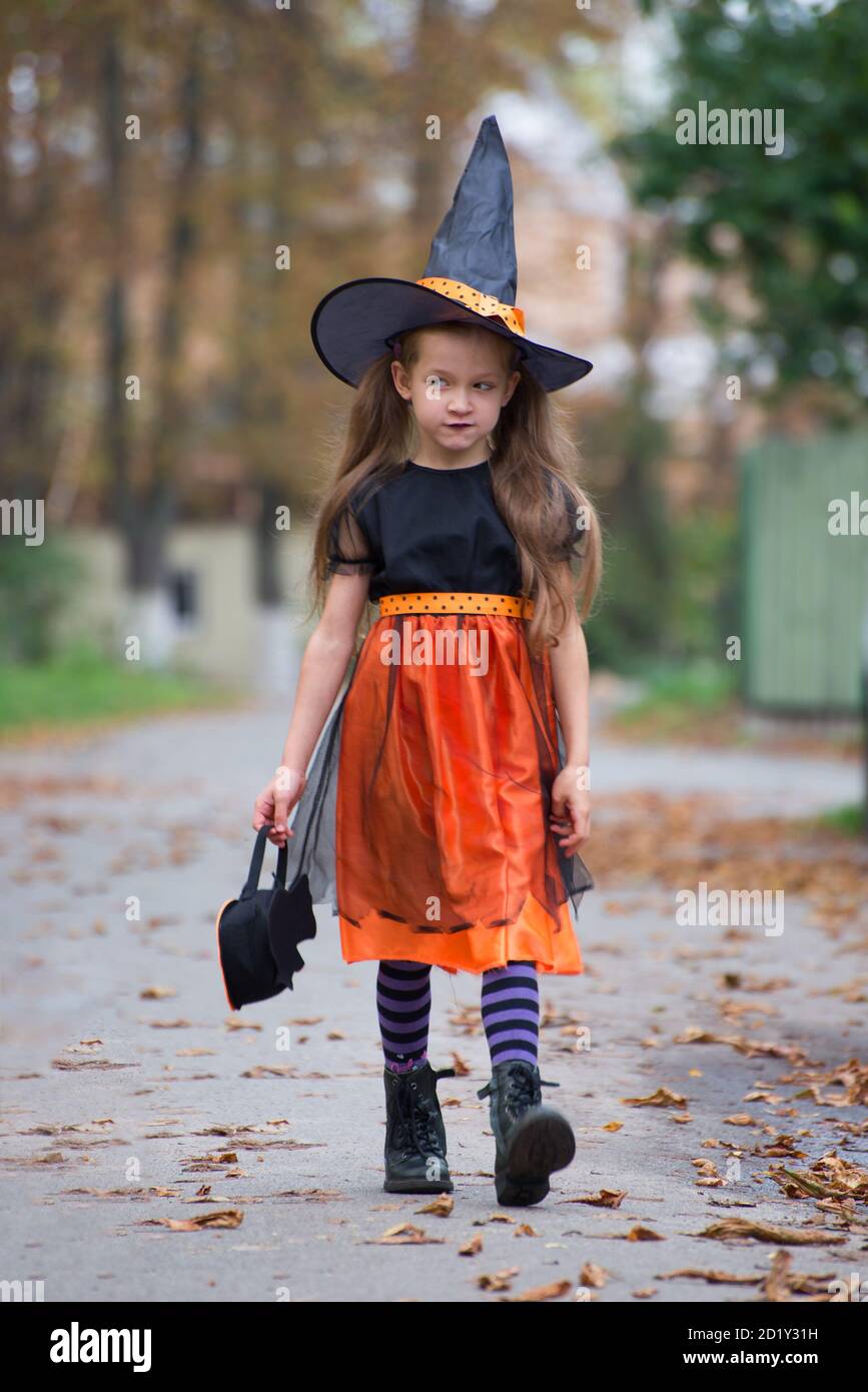 Bonne petite fille portant un costume de carnaval de sorcière et un panier  pour des bonbons tour ou de traiter près des portes de cour de voisin Photo  Stock - Alamy