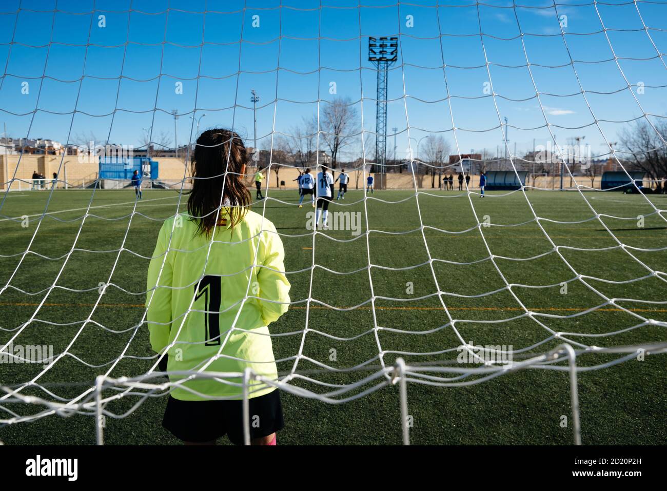 Gardien de but féminin debout sur le but. Des joueuses de football inreconnaissables jouent sur le terrain de football. Jeune femme équipe de football jouant à tourna Banque D'Images