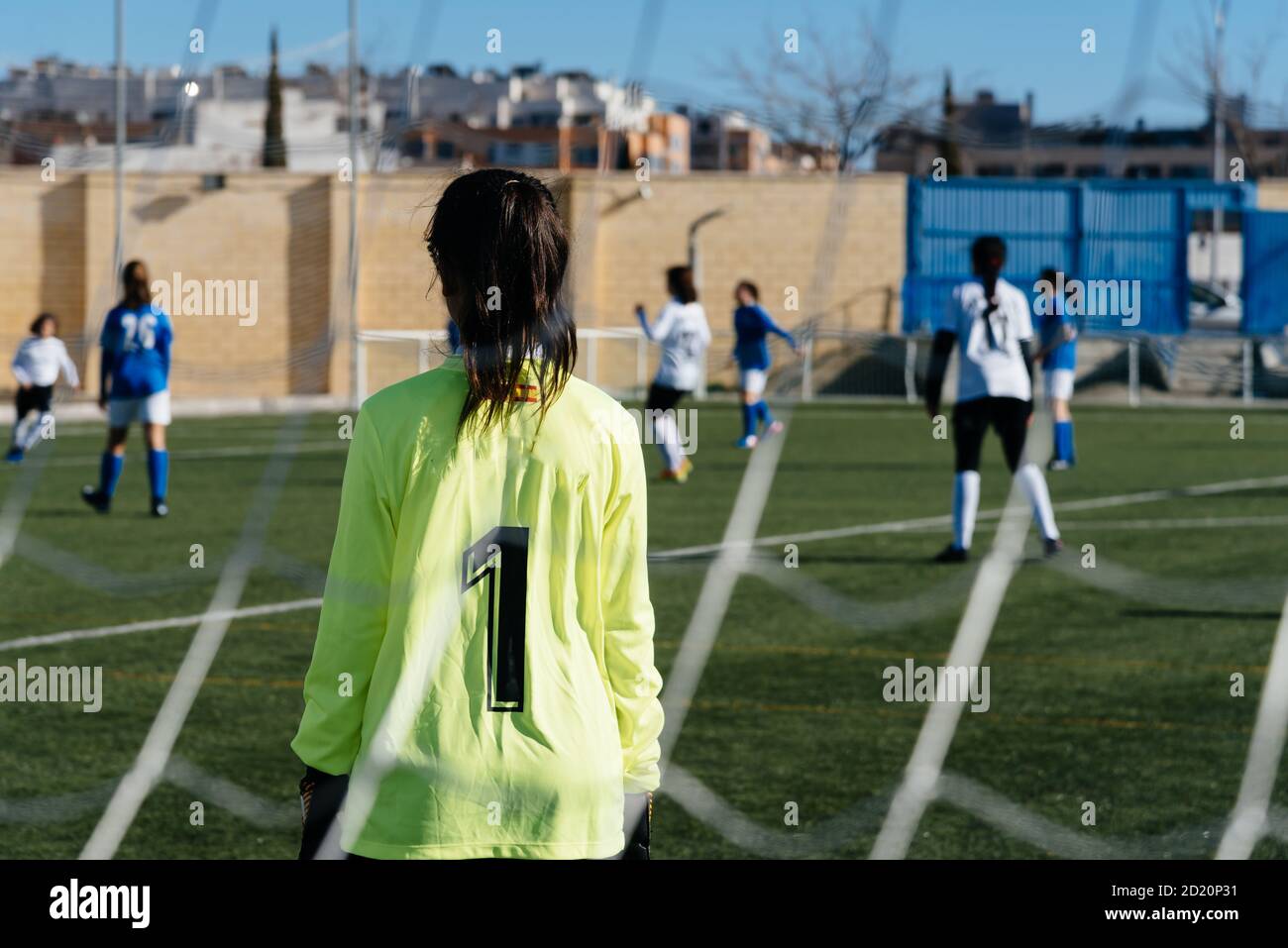 Gardien de but féminin debout sur le but. Des joueuses de football inreconnaissables jouent sur le terrain de football. Jeune femme équipe de football jouant à tourna Banque D'Images