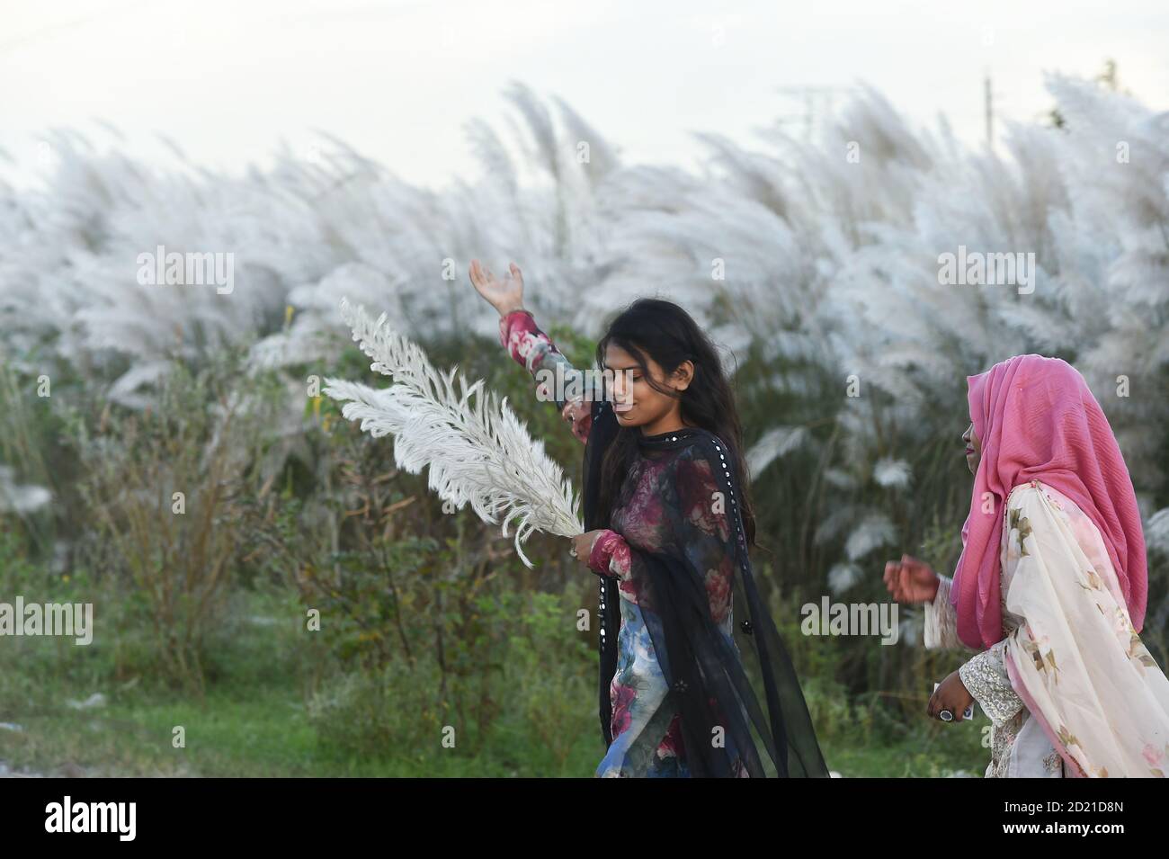 Dhaka. 6 octobre 2020. Les filles marchent devant les fleurs de Kans Grass à Dhaka, au Bangladesh, le 5 octobre 2020. Credit: Xinhua/Alay Live News Banque D'Images