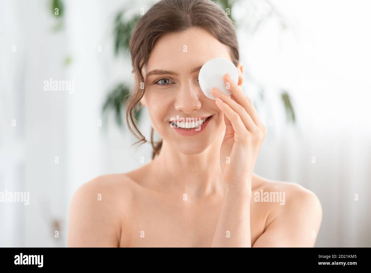 Joyeuse jeune femme enlever le maquillage de ses yeux Banque D'Images