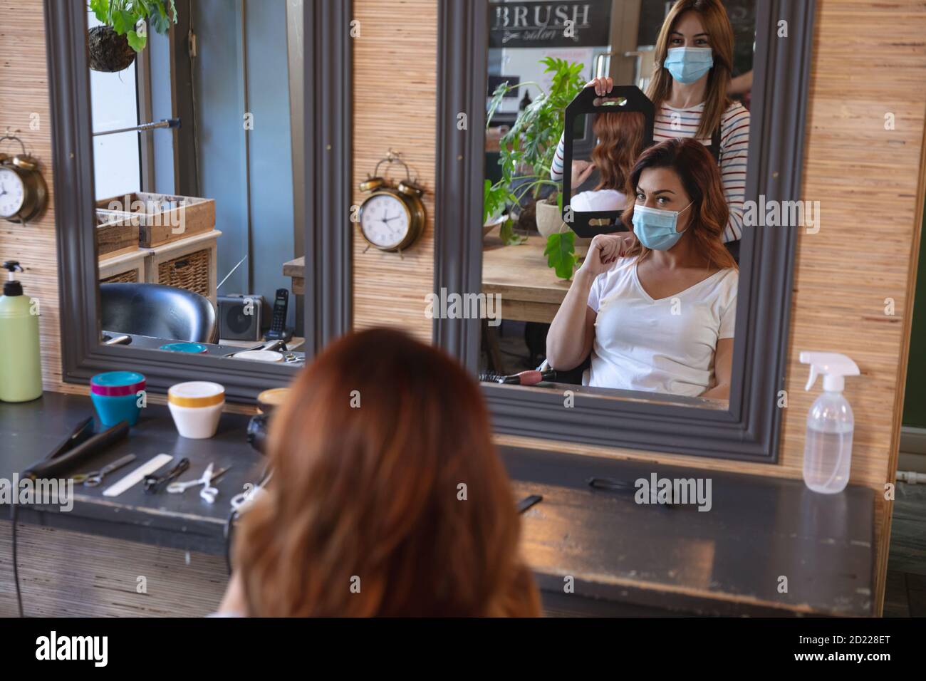 Coiffeur féminin montrant une coupe de cheveux à un client féminin utilisant un miroir Banque D'Images