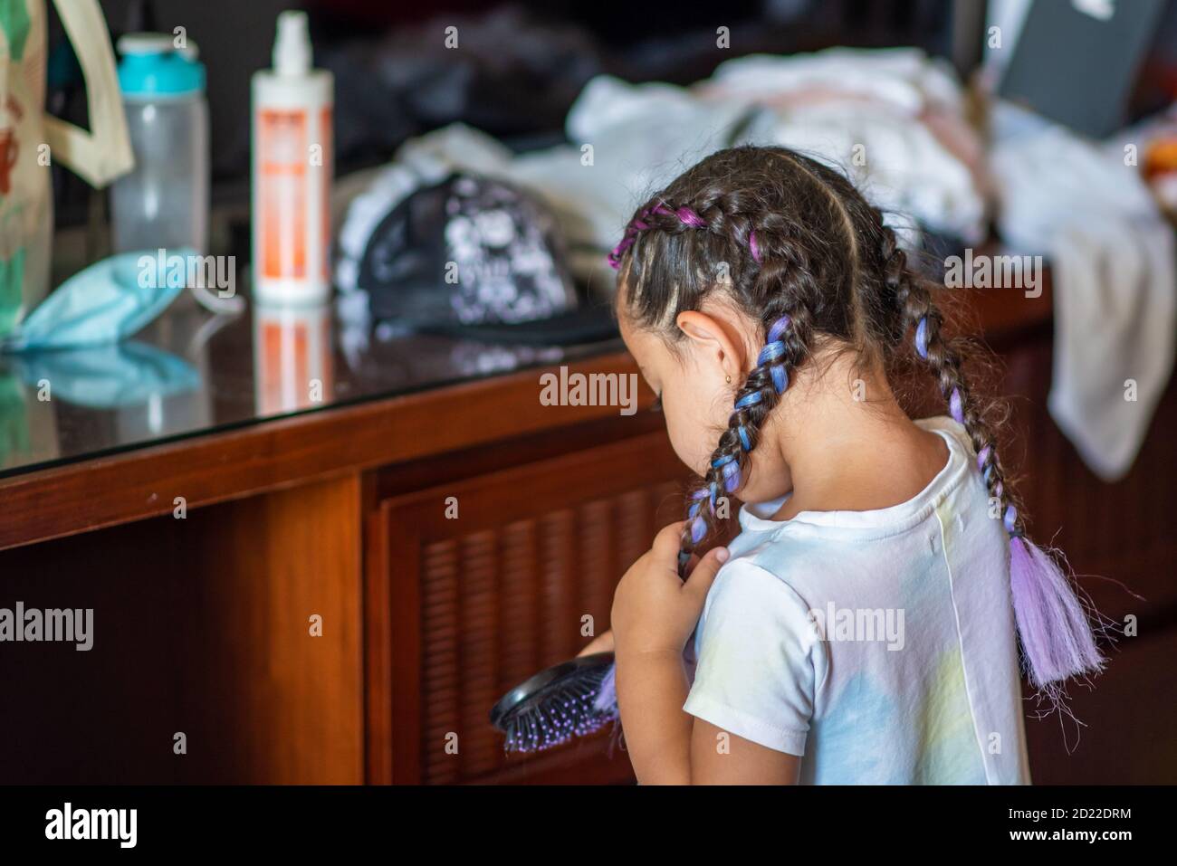 Image d'une jeune fille se peignant les cheveux et tressée. Banque D'Images