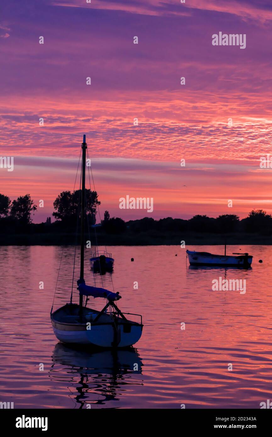 Bateaux à moteur et bateau à voile Norfolk Shrimper sur le port de Christchurch avec UN coucher de soleil rose et violet, Christchurch UK Banque D'Images