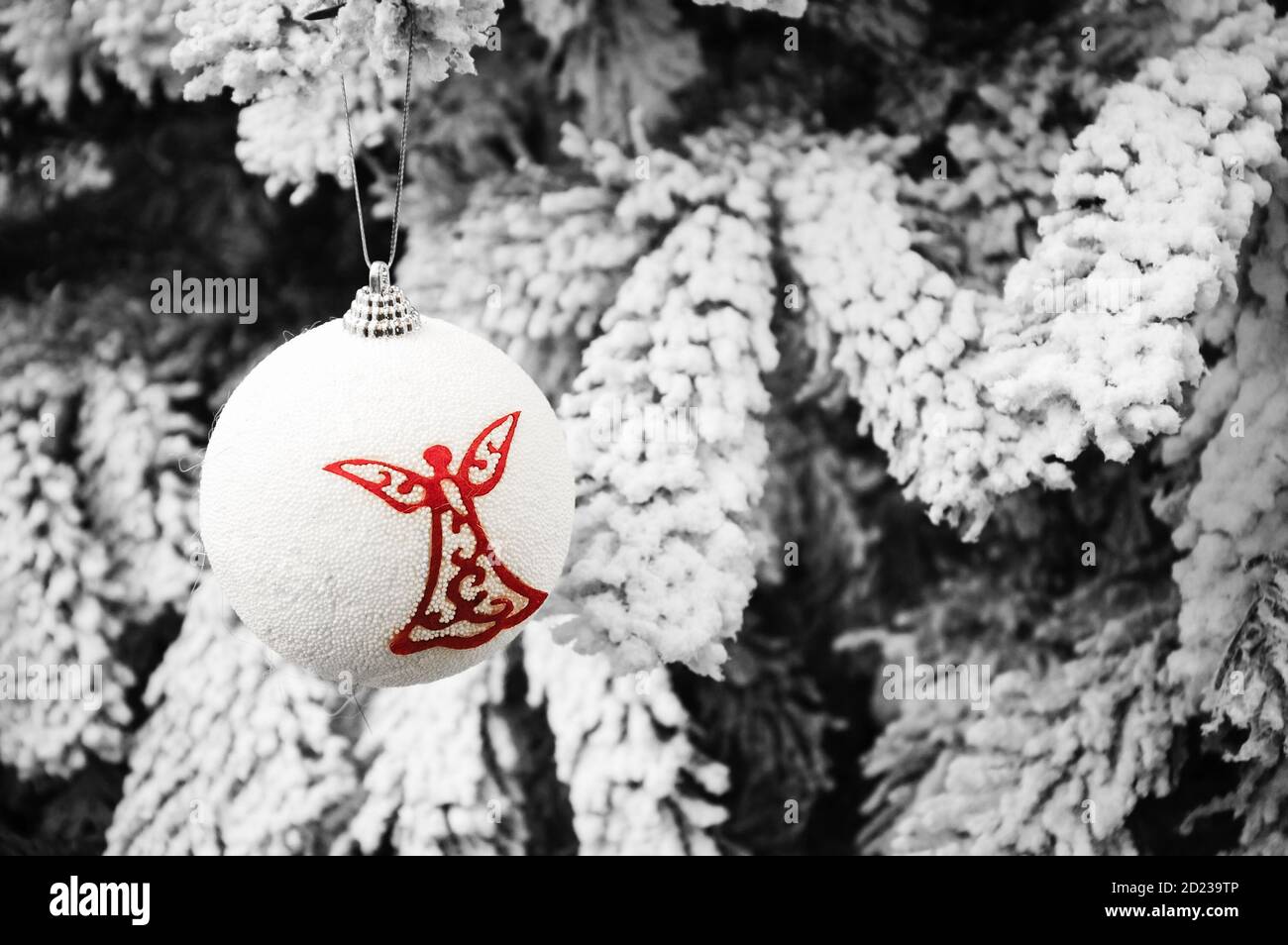 Boule vintage avec silhouette d'ange accrochée à l'arbre de Noël recouvert de neige. Carte de Noël vintage. Mise au point sélective. Photo en tons. Banque D'Images