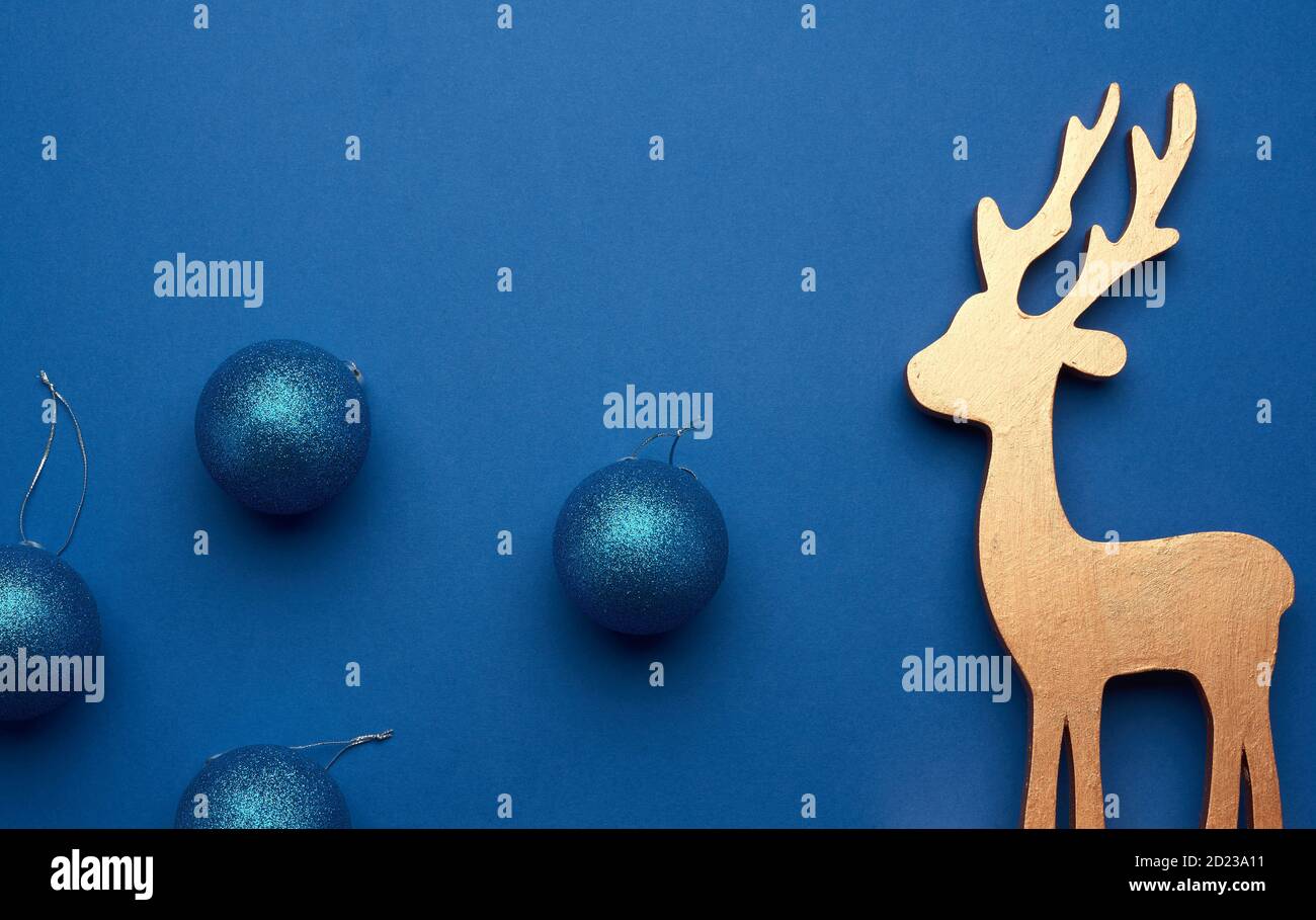 boules de noël bleues brillantes pour l'arbre et cerf en bois sculpté sur fond bleu, toile de fond festive Banque D'Images