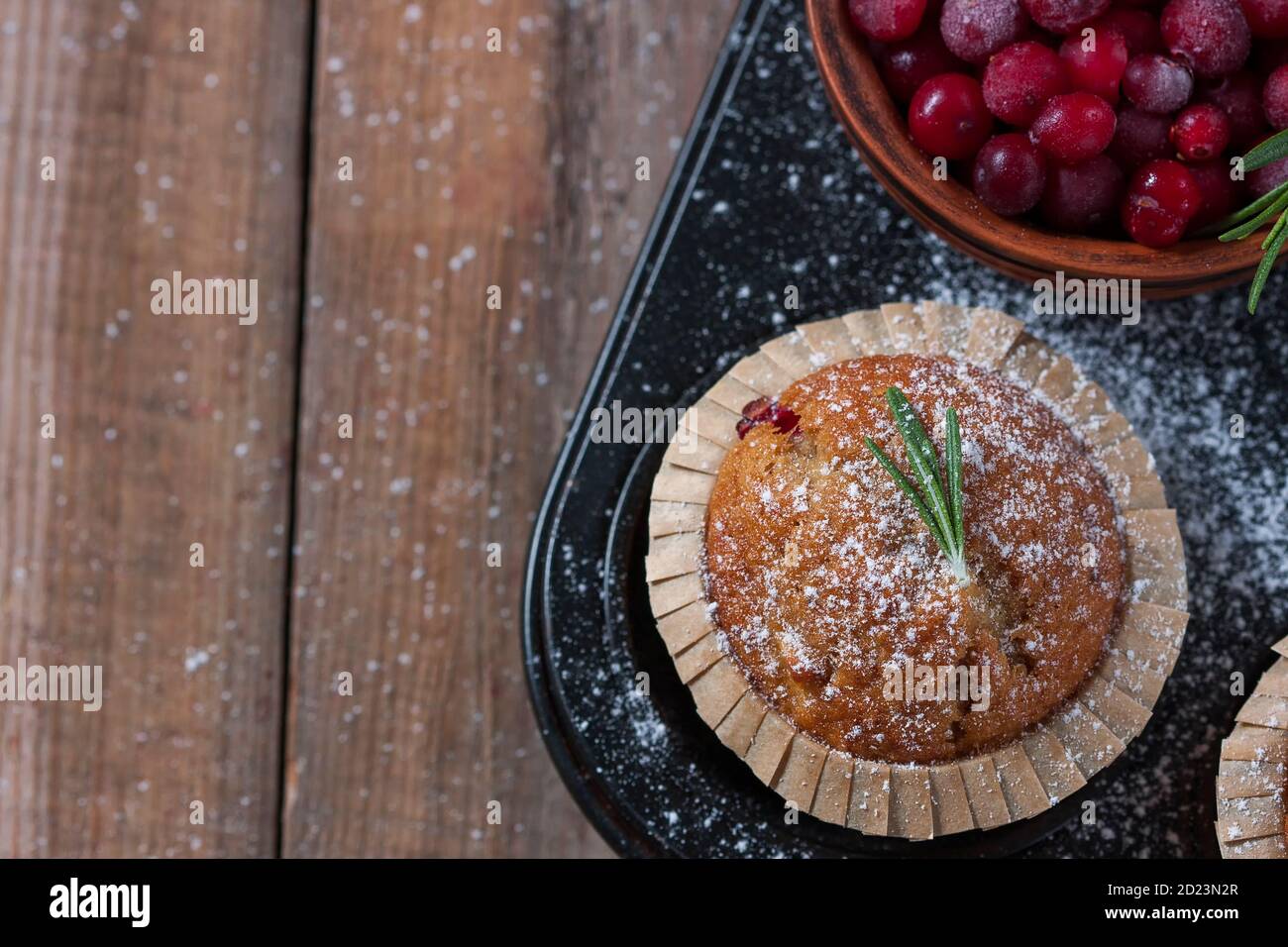 Muffins aux canneberges maison frais sous forme de pâtisserie sur une table en bois avec décoration de Noël. Muffins dans un emballage en papier recyclable écologique. Banque D'Images