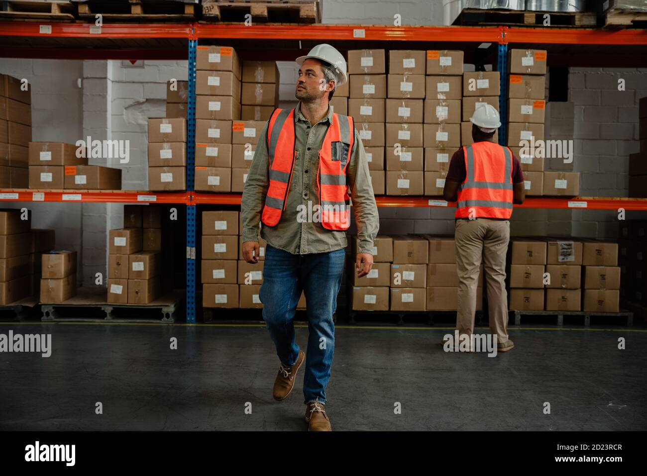 Portrait d'un ouvrier d'usine caucasien marchant autour du port d'entrepôt uniforme et casque Banque D'Images