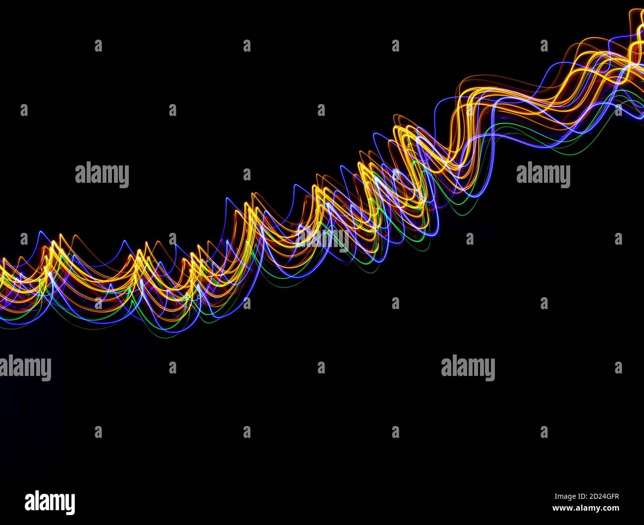Une longue exposition photo de couleur néon dans un abrégé swirl, motif de lignes parallèles sur un fond noir. La lumière peinture photographie. Banque D'Images