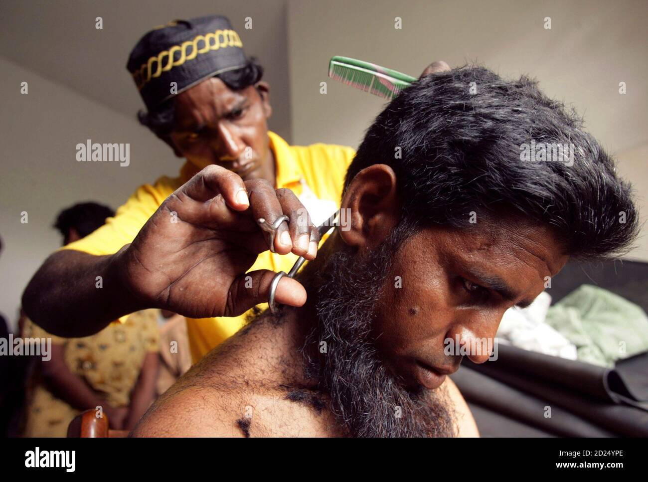 One of the Rohingya boat people, rescued off the coast of Indonesia's Aceh  province, has his hair cut by a friend at a temporary shelter in Idi Rayeuk  February 4, 2009. Indonesian